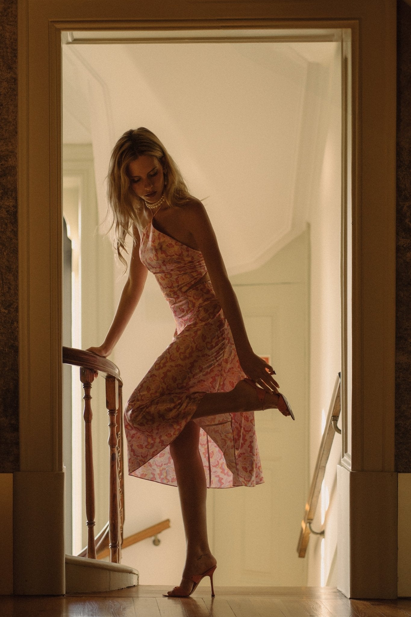 <img src="guavaglowskirtcampaign2" alt="A blonde Model in front of a hotel stairs, wearing a pink retro pattern satin skirt with a flattering bias cut styled with a matching top.">