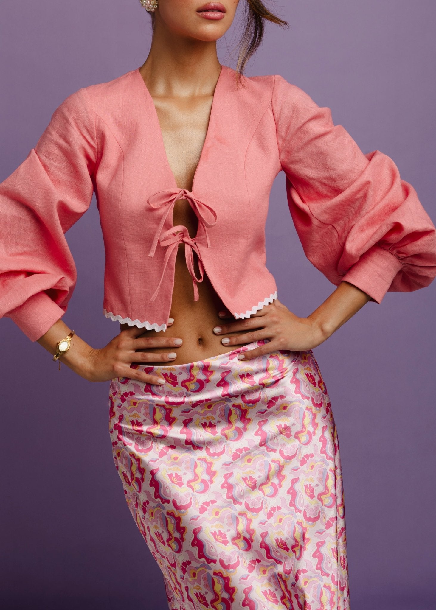 <img src="guavaglowskirtfulllookcloseup" alt="Close-up of a Model wearing a pink retro pattern satin skirt with a flattering bias cut. and a pink linen top.">