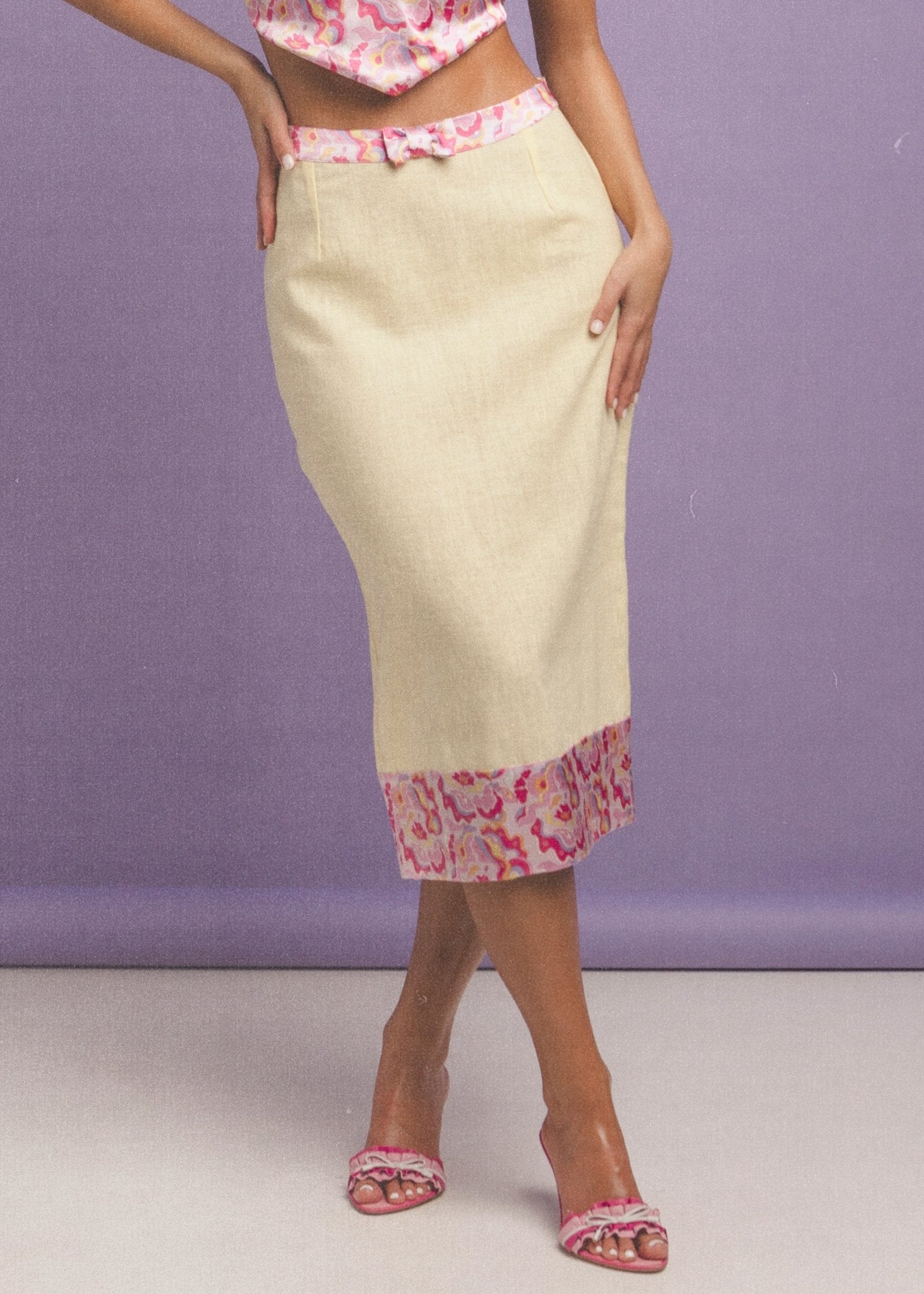<img src="sunnnychicskirtcloseup" alt="Close-up of a Model wearing a flattering yellow linen pencil skirt with a retro pattern on the hem and a bow detail on the belt .">