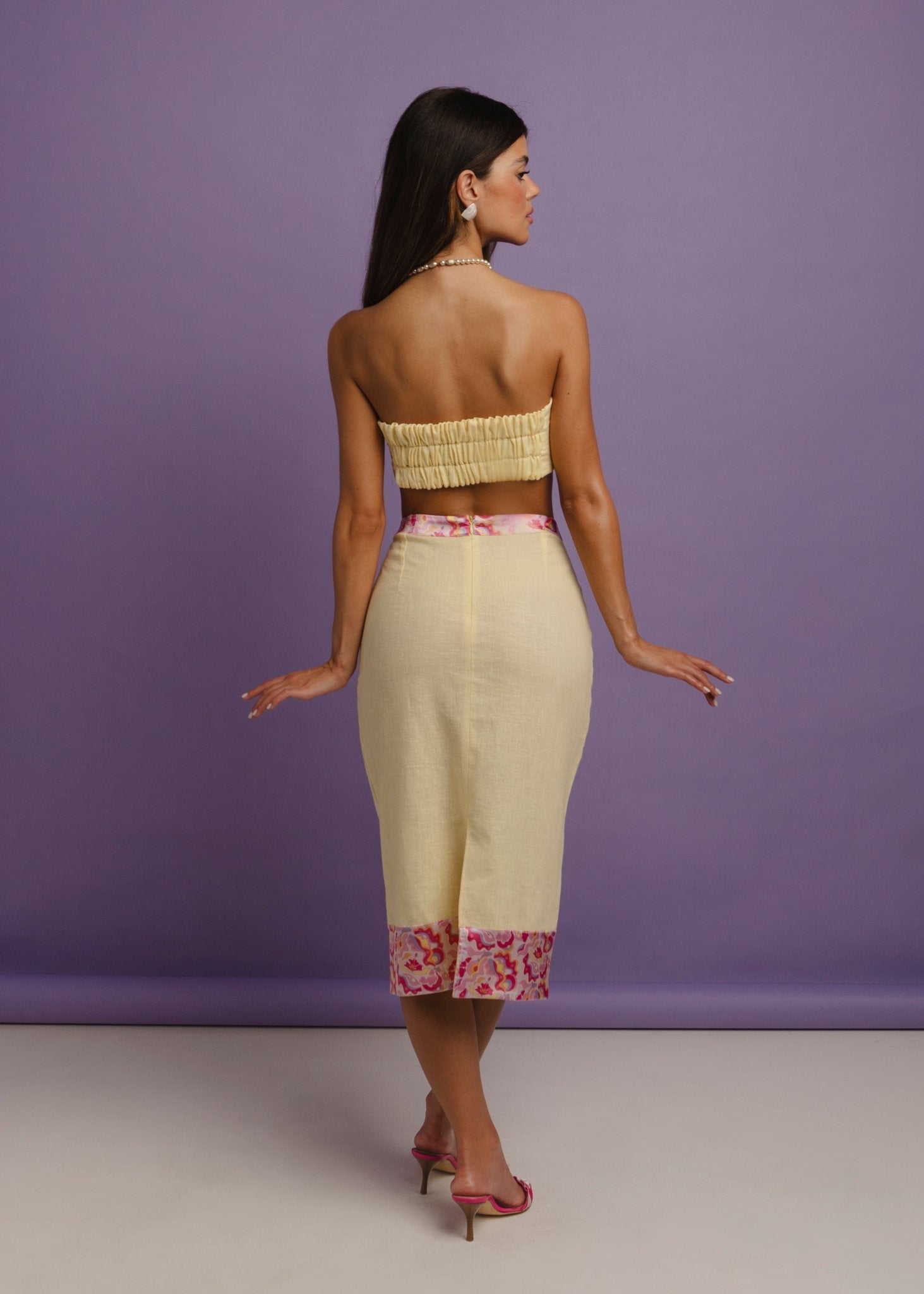<img src="sunnnychictopfullbodyback" alt="A back view of a Model wearing a yellow linen balconette style top with a shirring elastic back for stretch, styled with a matching skirt .">