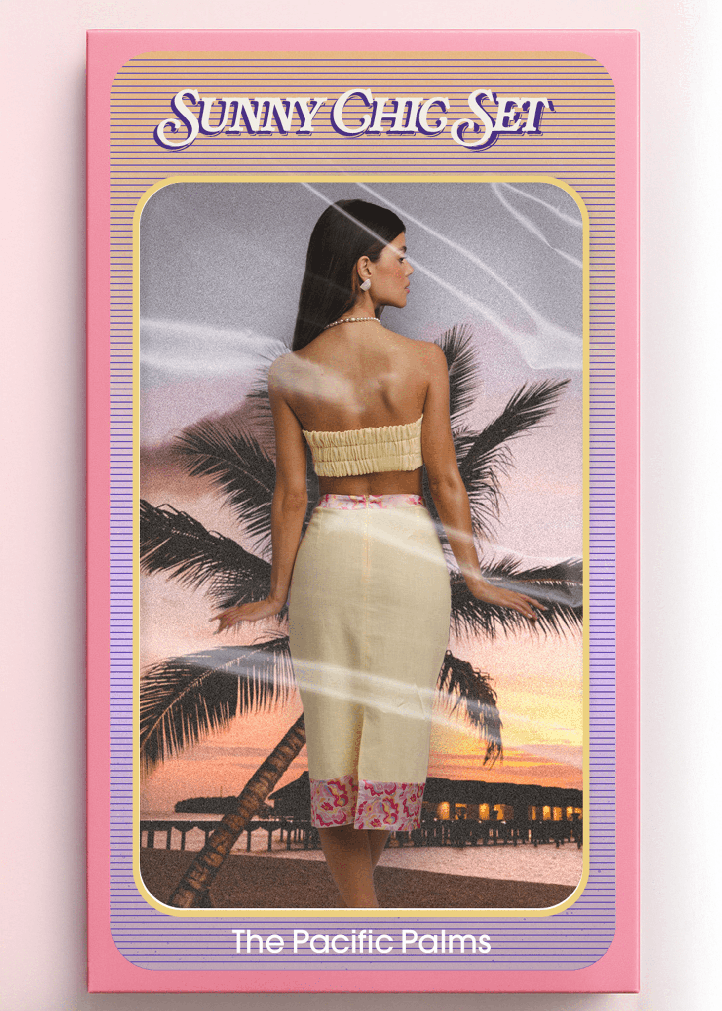 <img src="sunnychicsetback" alt="Sunny Chic Set – The Pacific Palms. Model shown from the back inside a vintage doll-style packaging box, wearing a yellow co-ord outfit with a retro pattern hem and front bow. Styled like a retro toy against a sunset beach with palm trees and overwater bungalows.">